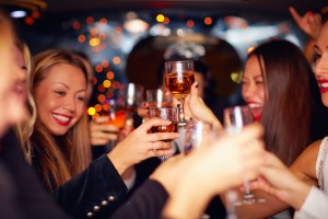 Beautiful Women Clinking Glasses In Limousine. Focus On Glasses